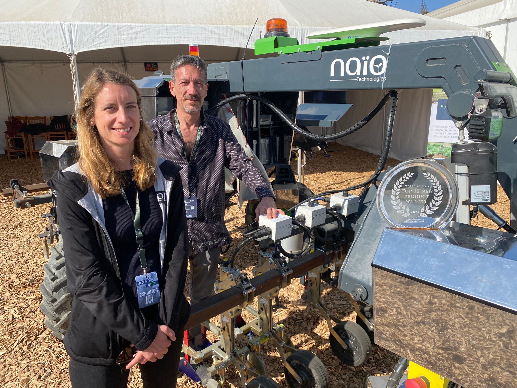  Ingrid Sarlandi and another member of Naio Technologies stand next to Orio, a top-10 product winner at the World Ag Expo this year. Orio is a straddle robot designed for row crops and beds of vegetables. 