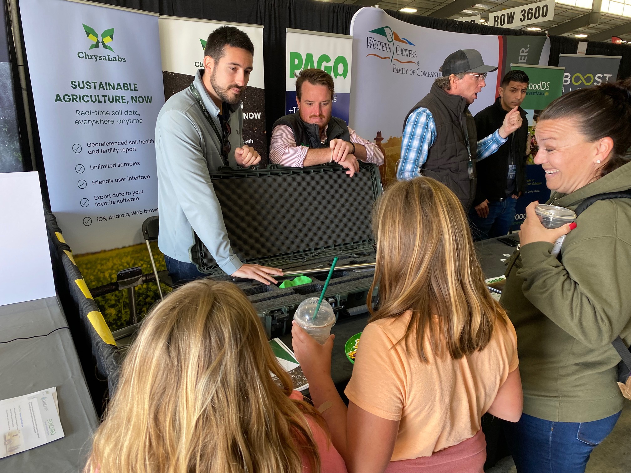 At the ChrysaLabs booth, team members explain the company’s technology to a family. ChrysaLabs provides georeferenced soil health and fertility data for growers. 