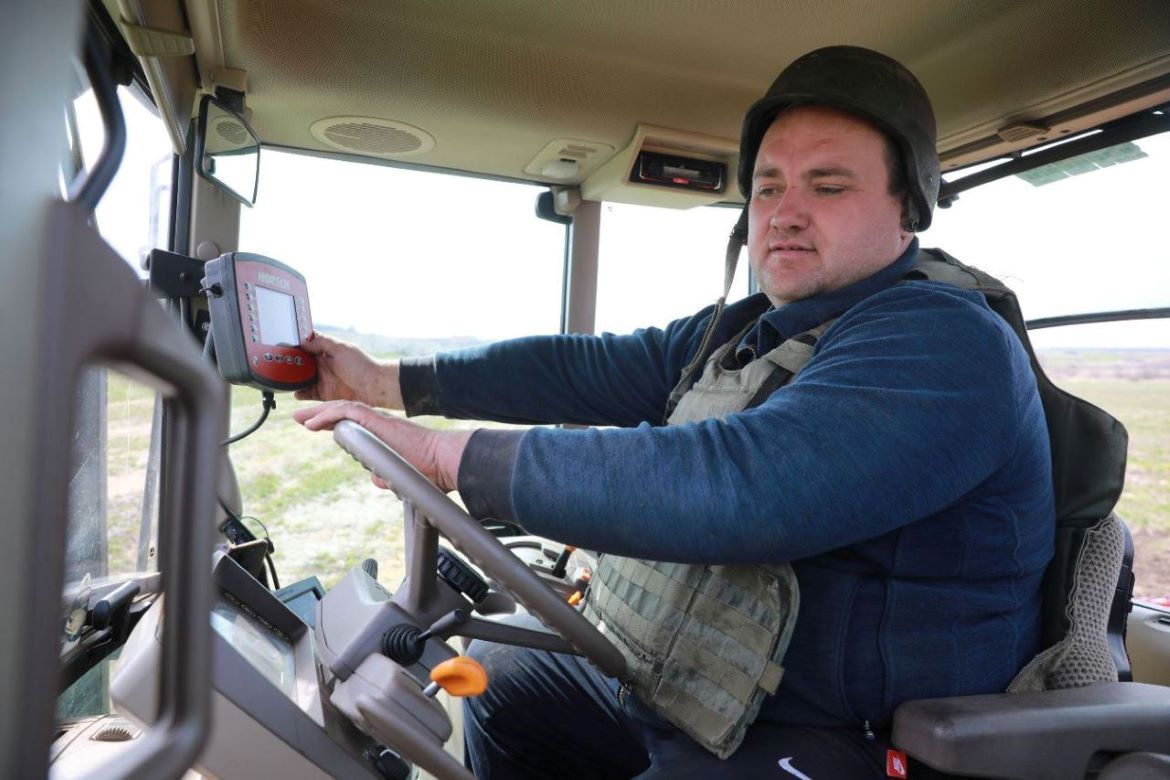  Ukrainian farmer wears helmet and flak jacket while in the tractor 