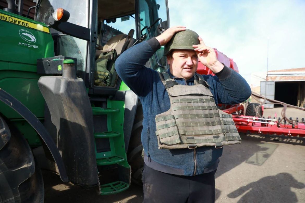  Ukrainian farmer putting on helmet and flak jacket before getting in the tractor