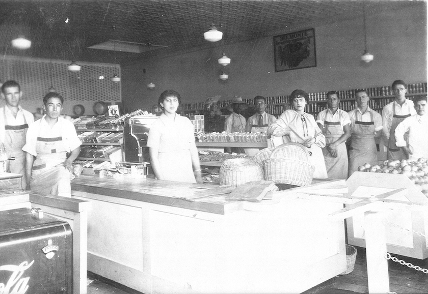  Supermarket employees stand near the checkout stations and produce bins at an early Bashas' grocery store in Chandler, Ariz.