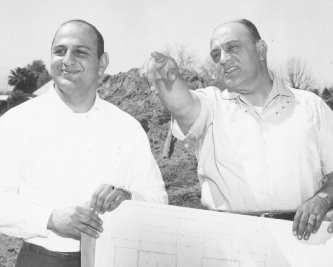  Eddie Basha Jr. holds what looks like building plans on a construction site with his father, Eddie Basha Sr.