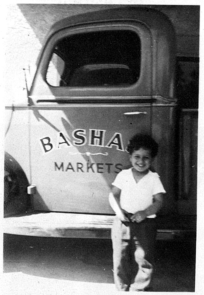  Little Eddie Basha stands in front of a Bashas' delivery truck in the early 20th century.