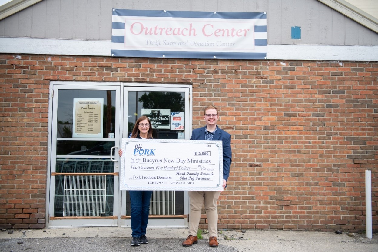 Janel Hord, from Hord Family Farms (left), presented a check for $2,500 to Kaden Thomas, executive director of New Day Ministries in Bucyrus, Ohio. The organization will use the funds to purchase pork to help provide high-quality protein for the families it serves in north-central Ohio.