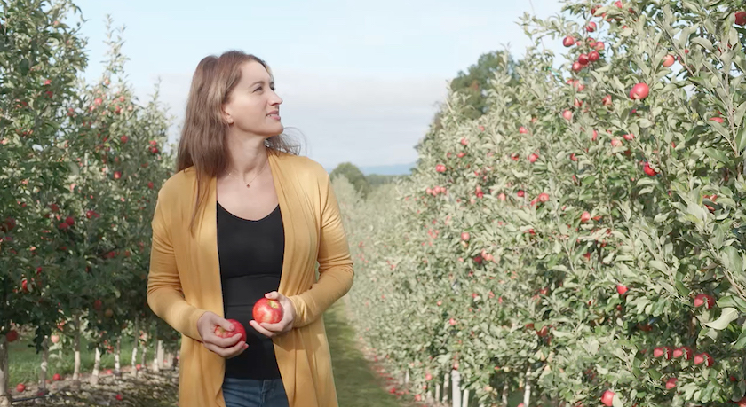 woman walks apple orchard in New York