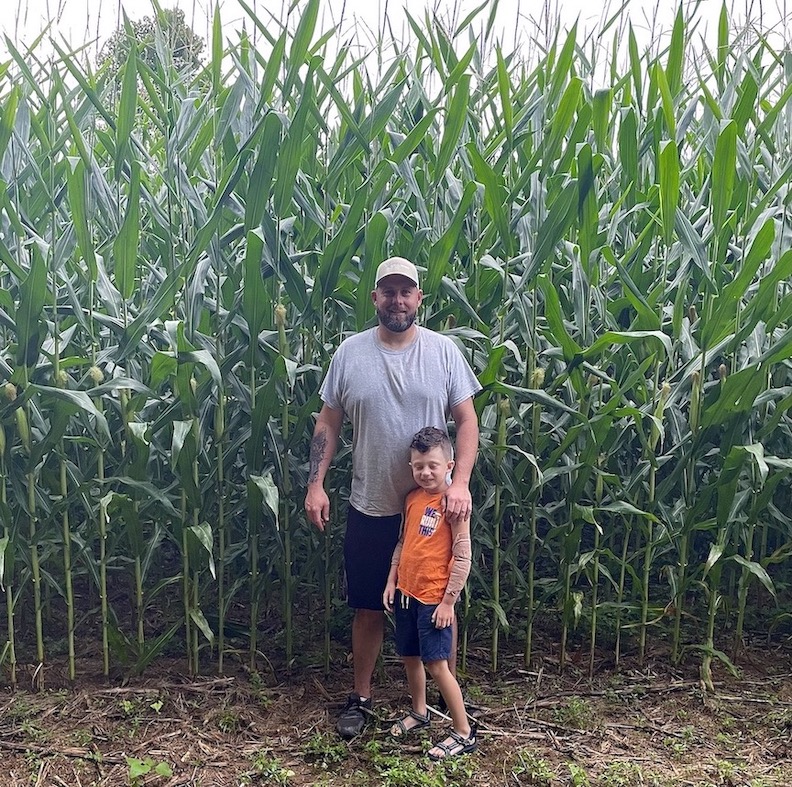 Russell Hedrick and Magnus beside a booming 40 acres of corn