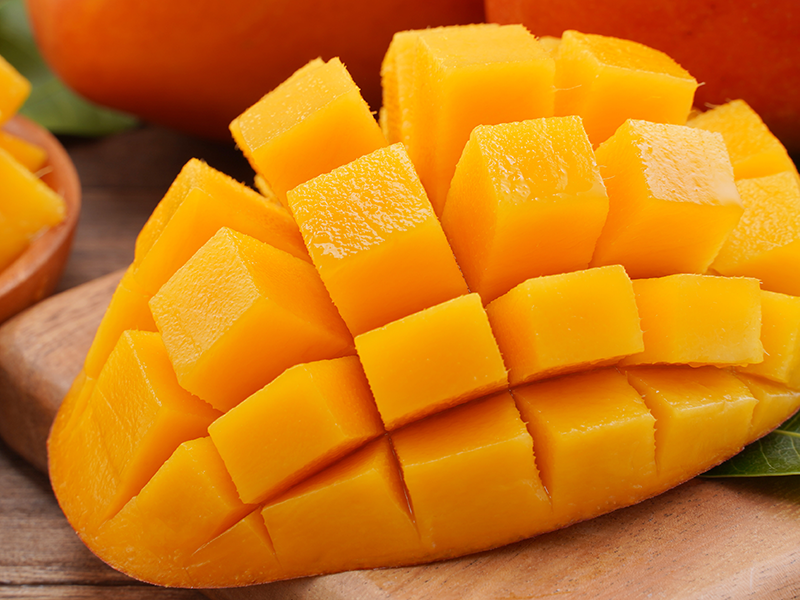 A mango cut into cubes, but the pieces are still attached to the skin.