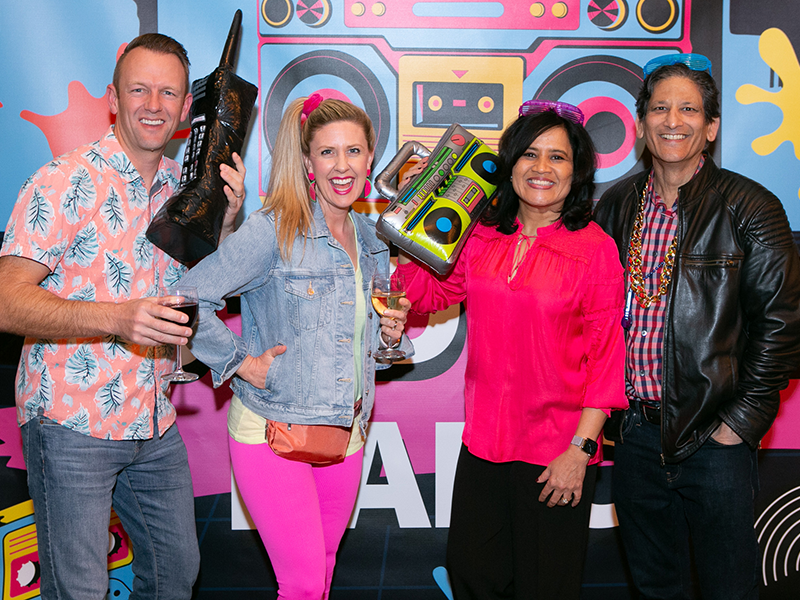 Four people at a 1980s-themed event