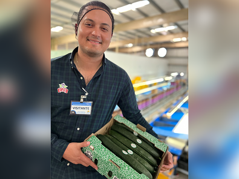 Man holding box of cucumbers in a warehouse