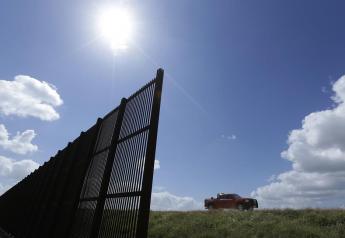 In this Sept. 6, 2012, file photo, cotton farmer Teofilo "Junior" Flores drives his truck along the U.S.-Mexico border fence that passes through his property in Brownsville, Texas.