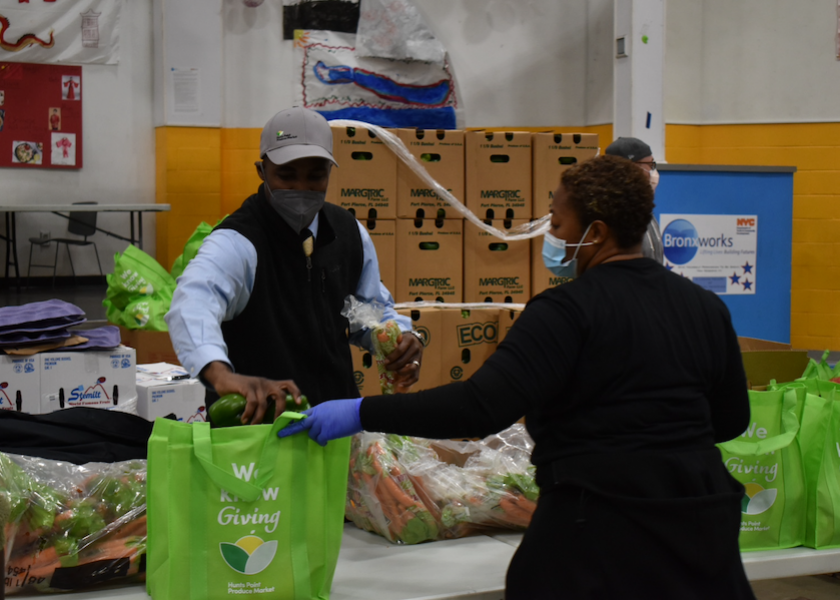 Bronx, N.Y.-based Hunts Point Produce Market CEO general manager Phillip Grant packs a bag held by a woman for one of several donation events for the annual Hunts Point Week of Giving, in advance of Thanksgiving.