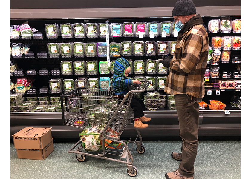 A customer checks his list while shopping with his son at a supermarket in New York. Retailers nationwide are experiencing product shortages, and customers are noticing spotty shelves in produce departments.