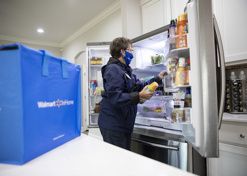 A Walmart associate places groceries inside the customer's refrigerator in the home.