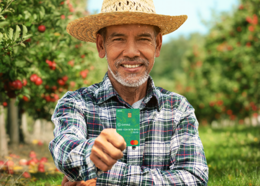 A farmworker holds a Ganaz payroll card. 