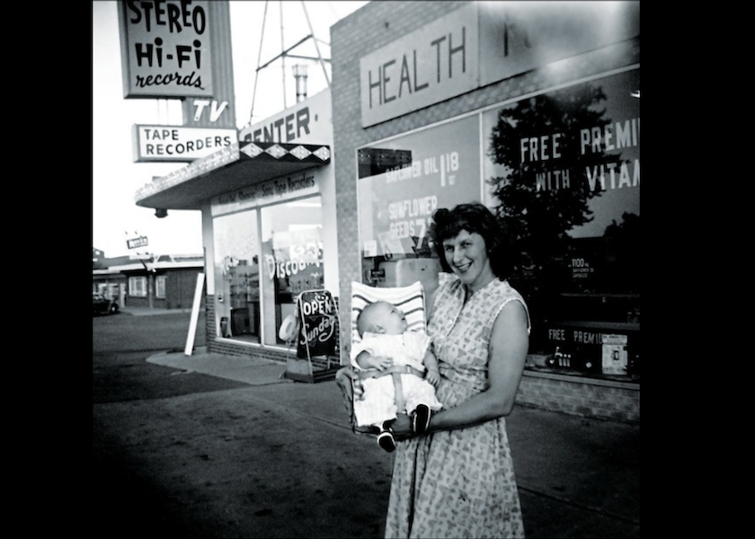 Natural Grocers Cofounder Margaret Isely stands outside the first brick-and-mortar store, circa 1958, with a baby.