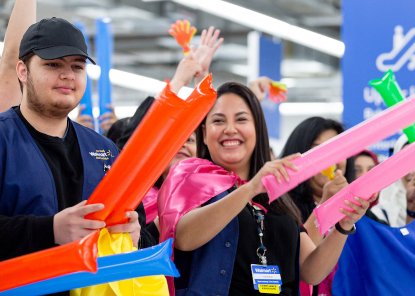 Several Walmart Canada employees wave colorful blow-up items in a celebratory event.