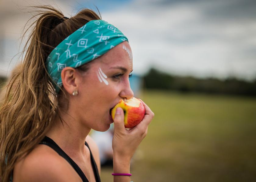 A Wanderlust 108 attendee enjoys an apple at a 2017 event in Austin, Texas, the first such event in which Rainier Fruit participated.